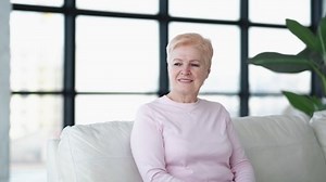 L'amour de la famille. Joyeuses femmes. Soutenir la relation. Fille souriante embrassant tendrement sa mère en parlant pendant qu'elle est assise dans le canapé, à l'intérieur du salon.