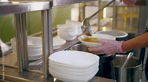 buffet restaurant. self-service cafeteria. close-up. waitress, in protective gloves, pours hot soup into a bowl for customer. cooking. health food.