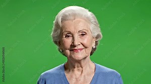 Smiling senior woman portrait on green screen background, confident elderly female with gray hair on chroma key studio backdrop
