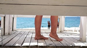 Woman in the changing, dressing room on beach, at sunset on the seashore. Close-up of bare female feet legs in enclosed changing room cabin. Summer holiday vacation and travel concept. Slow motion
