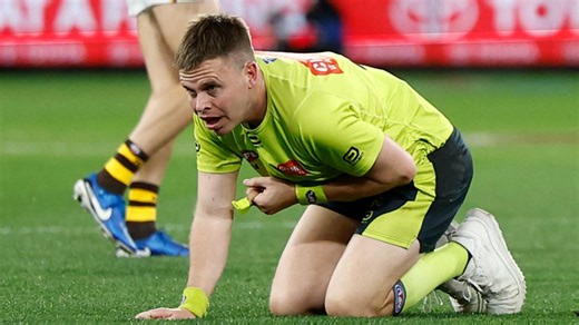 AFL umpire Nick Foot is cleaned up by Bulldog Aaron Naughton.