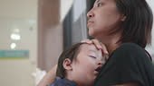 Asiatische Mutter umarmt ihren Sohn, um auf der Brust zu schlafen....