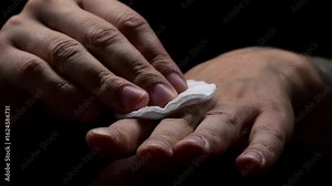 A man wipes his hand with a cotton pad to disinfect a wound or scratch on his hand. Using hydrogen peroxide or zorhexedine to disinfect a wound. Health and care for the code.