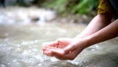 Woman washing hands at waterfall