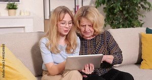 Granddaughter teaching grandmother how to use tablet . Teen girl and senior woman have leisure time together. Family, relation, communication, technology, education concept
