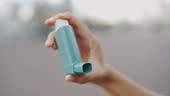 Young woman using asthma inhaler while traveling , living with lung...