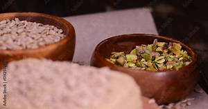 halva from roasted sunflower seeds, wooden bowl , a sweet delicious dessert made from fried sunflower seeds with pistachios