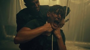 Male criminal or killer fighting with man and strangling him with wires in underground room with flickering LED lamps. Scene from action movie