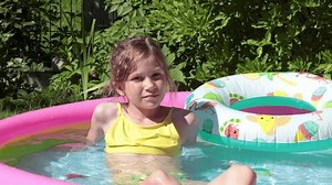 Young girl swimming in inflatable pool in summer. Children and water games. Family and love. Summer fun.