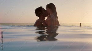romantic couple kissing in swimming pool enjoying honeymoon vacation at luxury hotel with beautiful view of mediterranean ocean at sunset 4k