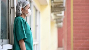 Tired depressed female asian scrub nurse wears face mask blue uniform sits on hospital floor,Young woman doctor stressed from hard work