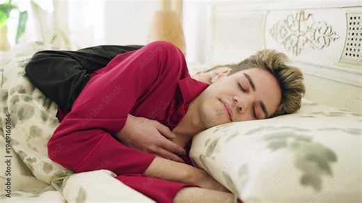 Young gay male couple sleeping peacefully in bed together in the morning. Affectionate lovers enjoying a sweet and tender romantic moment