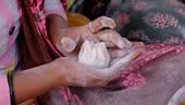 Woman making sweet rice modak stuffed with grated coconut and...