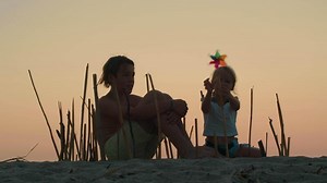 Siblings constructing bamboo enclosure at sunset