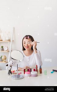 Attractive talented female blogger reviews beauty product for video blog, gives advice to girls and women, films process on camera Stock Photo - Alamy