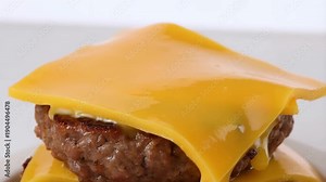 Close-up slow motion of melted cheddar cheese sliding over a hot grilled beef patty on a burger stack with glossy gooey texture, perfect for food commercials and culinary content