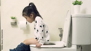 Little asian girl sitting on the flush toilet in the white bathroom and learning how to use the toilet by yourself, Teaching Your Child for Parents, KidsHealth Concept , Slow Motion footage