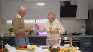 Playful elderly couple dancing in kitchen, enjoying fun time, happy marriage