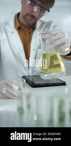 Man scientist wearing white protective gloves is holding a yellow chemical solution inside an Erlenmeyer flask in a laboratory, vertical portrait. Science and medicine concept Stock Video Footage - Alamy
