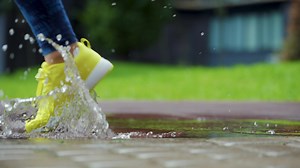 Female sports woman jogging outdoors, stepping into puddle. Single runner running in rain, making splash. Slow motion