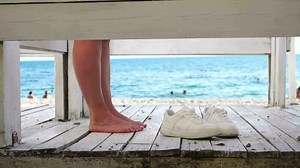 Woman in the changing, dressing room on the beach, at sunset on the seashore. The girl changes clothes, throwing up a swimsuit, then leaves the locker room in a pink dress. Close up, slow motion