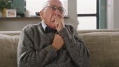 4k video footage of a senior man coughing while sitting at home