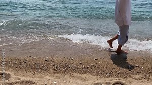 Slender female legs and feet walk on the sea waves on a sandy beach. Pretty woman walking on the seashore. High quality 4k footage.