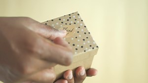 Download hand putting a thank you sticker on a gift box for free