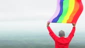 L’homme lever arc-en-ciel couleur LGBTI drapeau ondulant dans le vent...