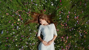 Young Woman Lying Peacefully in a Field of Wildflowers | Premium Stock Video Footage