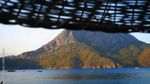 Beatuful sea view with luxury yahct, boats and island on background through thebeach umbrella. Paradise place for summer vacation in Mediterranean sea.