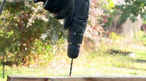 A male construction worker drills a hole into a board