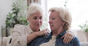 Mature lesbian couple at home on sofa
