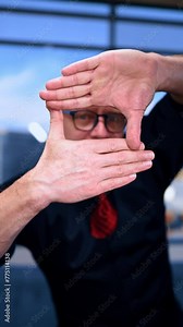 Adult male looking through the window made with his fingers. Portrait of a man peeping at you. Close up. Vertical video.