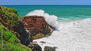 Australian coast, view from a cliff to the blue ocean with a rocky shore on a sunny day. Sea landscape, waves crashing on volcanic rocks at the shore.