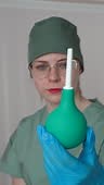 A close-up view of a female doctor holding an enema, also known as a...