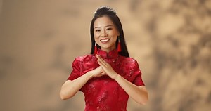 「赤いチョンサムの若いアジアの美女のポートレート。カメラに明るくほほ笑み、手で中国人の挨拶をする。 お祝いのしるしをしている美しい幸せな女の子。」の動画素材（ロイヤリティフリー）1061861971 | Shutterstock