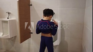 the boy peeing to toilet bowl in restroom