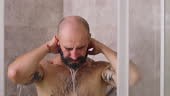 Backside view of man with muscular body takes shower, tropical...