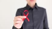 Woman hand holding red ribbon symbol of fight against hiv closeup 4k...