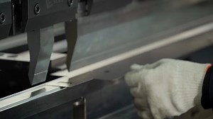 Operator places a metal sheet on a machine that folds it slowly on each side to create Rectangular Tube. Automated Metal folding and Bending Machine. Manufacturing Process. Precise Machining. Close up