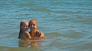Two children's girls swim in the sea and pose for the camera, hugging. Happy childhood. Two girls, sisters, are resting on the sea, swimming.