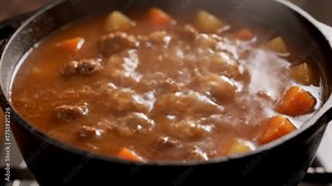 Simmering Beef Stew With Potatoes and Carrots in Cast Iron Pot on Stove Top