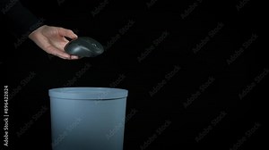 Put computer mouse in plastic trash. A view of female throw the e waste of computer mouse into the plastic trash on the black background.