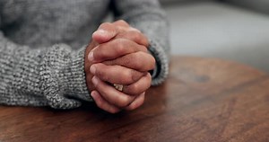 Close Up of Hands Clasped on Table
