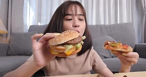 Close up asian woman takeaway eating junk food hamburger and pizza