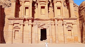 Caucasian woman tourist walk by explore Ad Deir or El Deir, the monument carved out of rock in the ancient city Petra, Jordan. UNESCO World Heritage Site