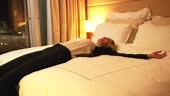 Happy and tired businesswoman jumping on the bed in hotel room....