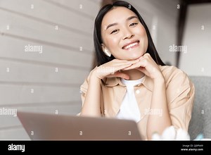 Cute smiling asian girl working from home on laptop, watching video with earphones on computer, doing homework or video chatting Stock Photo - Alamy
