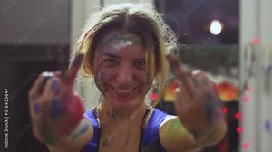 Portrait of a female artist. Girl with clumsy clorful painted face showing middle fingers.